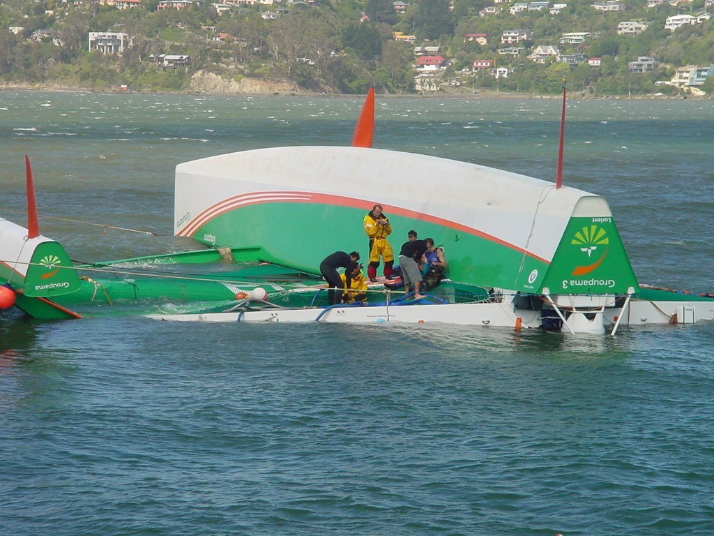 Groupama 3’s crew busy pumping the residual water from inside the main hull © Martin Balch